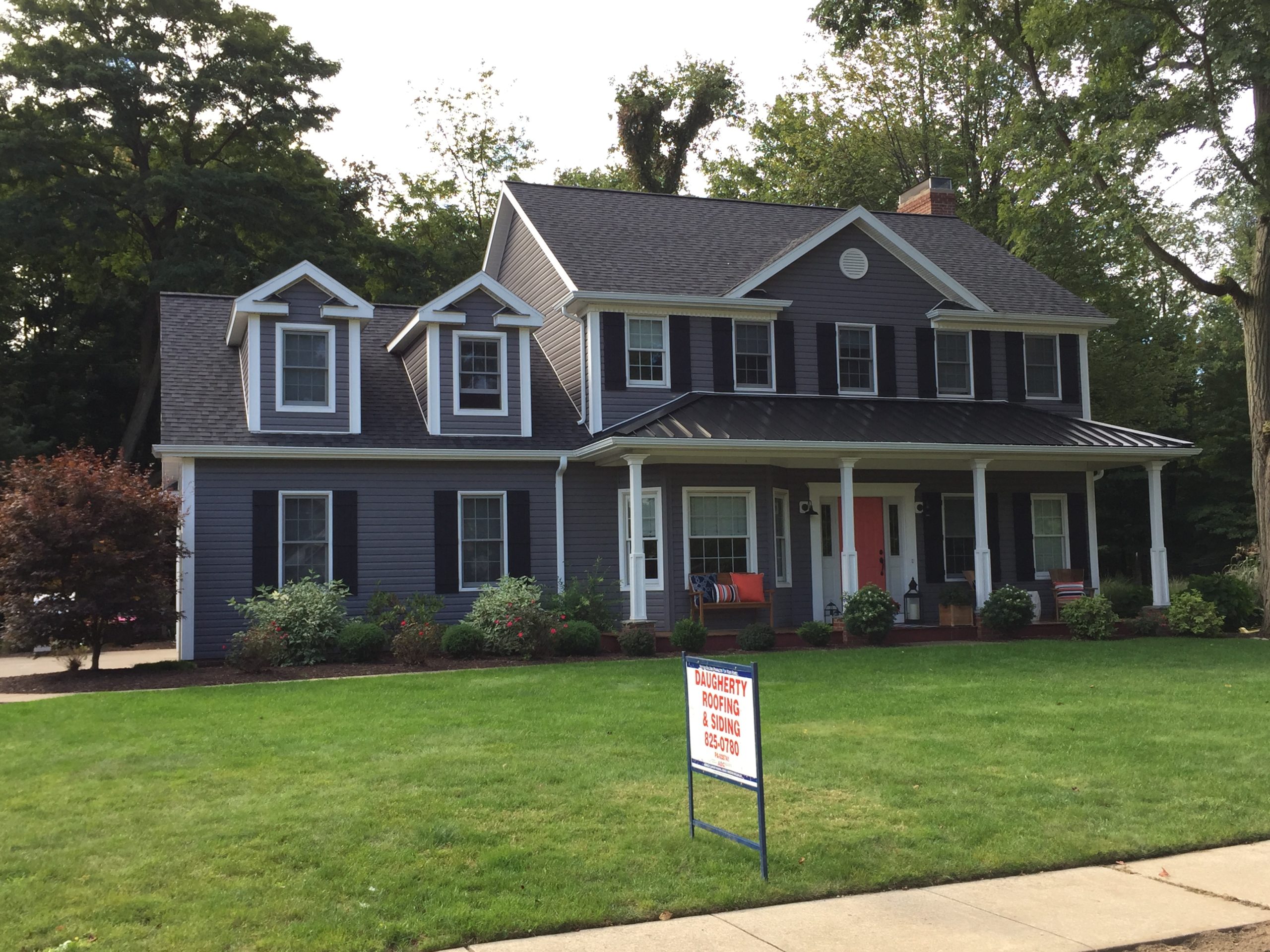 Home in Erie, PA with a standing seam metal roof over the large front porch and Certainteed shingles covering the rest of the house. Roofing project completed by Daugherty Roofing 814.